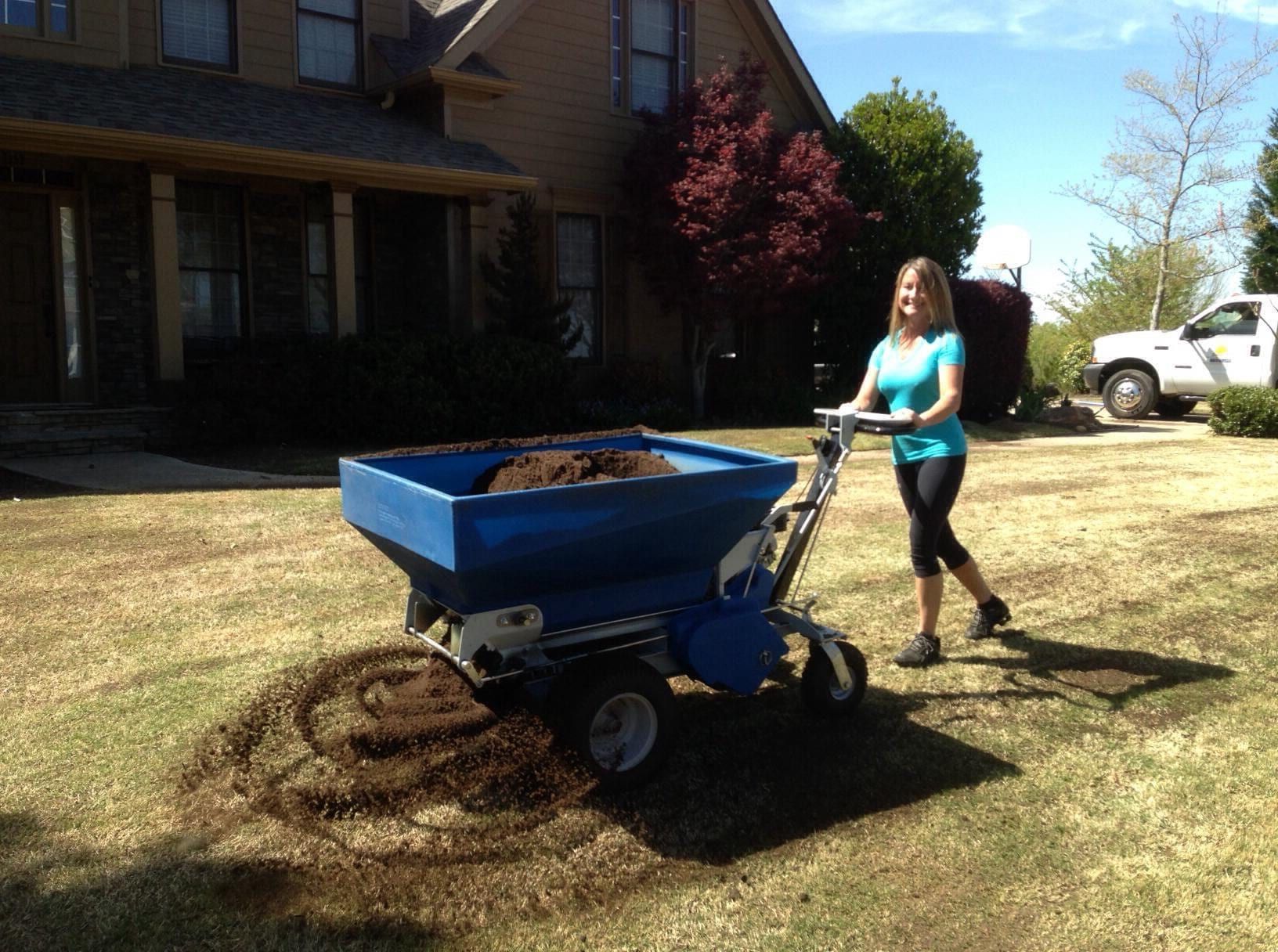 Spreading compost over a lawn with a walk-behind topdresser