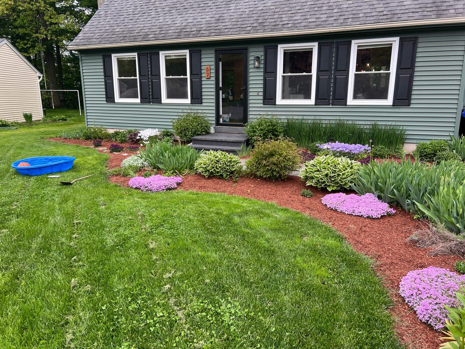 A front lawn edged with mulched beds and pink phlox